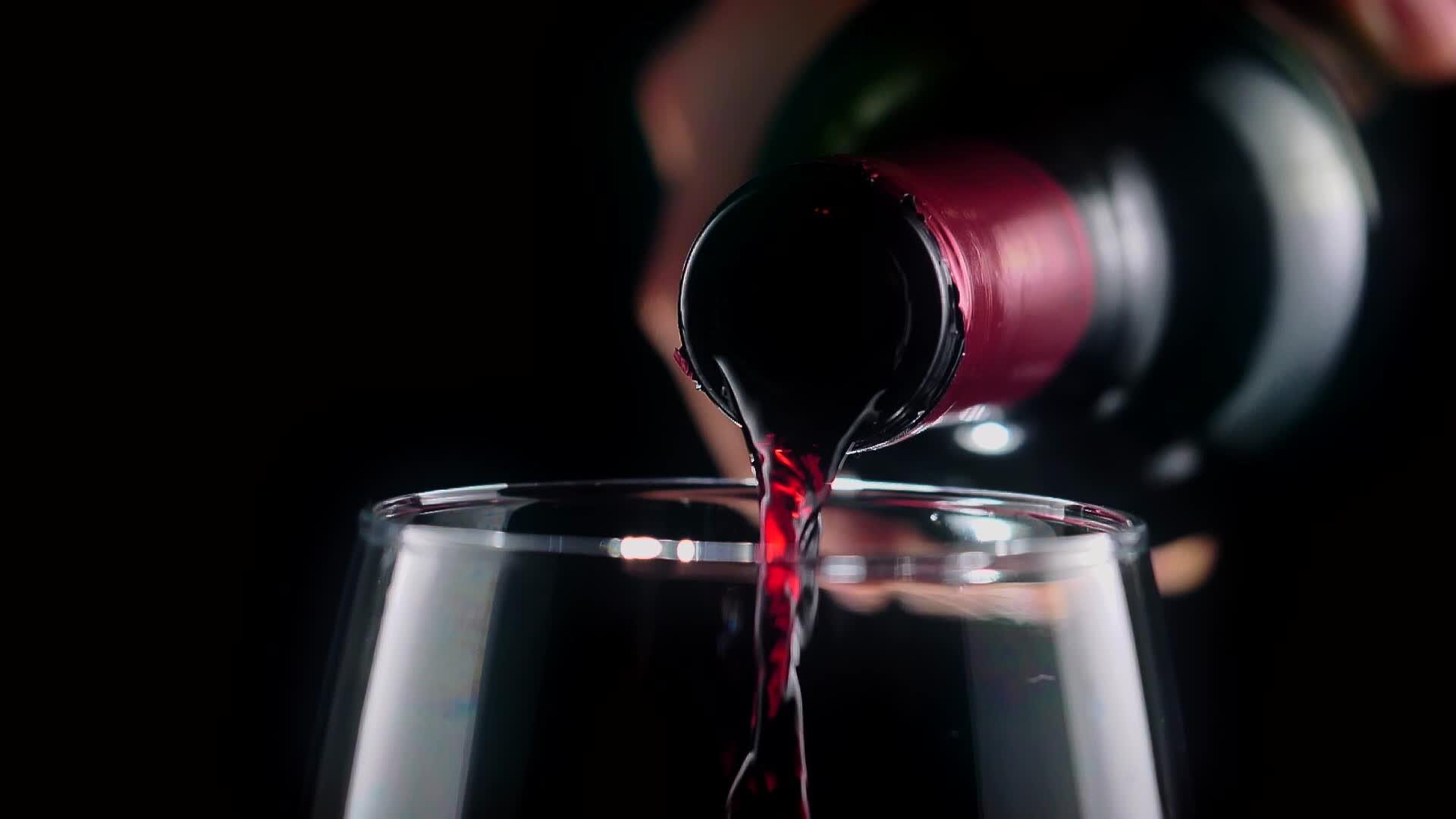 Rotwein wird bei Kerzenlicht in ein Glas gegossen — deseo tapas bar